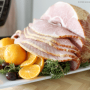 an Instant Pot Ham on a white tray with a basket of rolls in the background