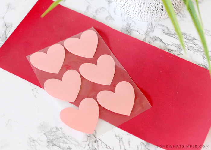 pink heart stickers on a red sheet of vinyl