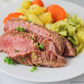 corned beef and cabbage plated on a white plate with steamed veggies on the side