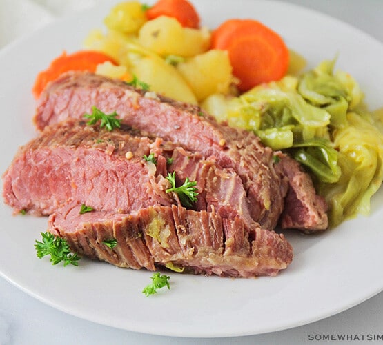 corned beef and cabbage plated on a white plate with steamed veggies on the side
