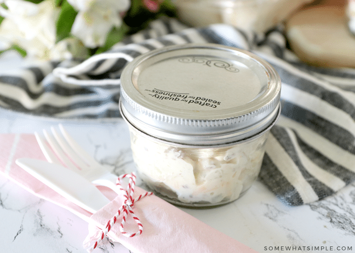 potato salad in a mason jar with plastic ware on the side