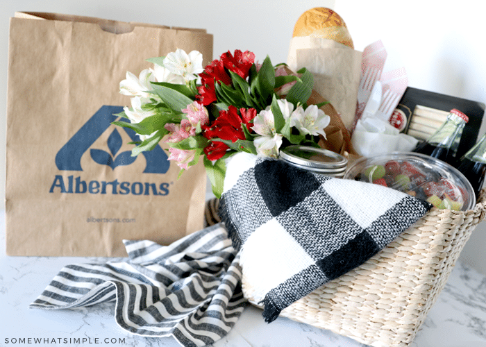 picnic basket filled with food and a blanket next to a brown grocery bag