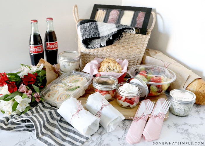 an array of food laid out with a picnic basket for a picnic date