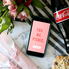 cell phone next to a bottle of soda and picnic supplies