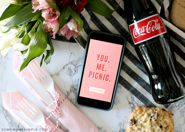 cell phone next to a bottle of soda and picnic supplies