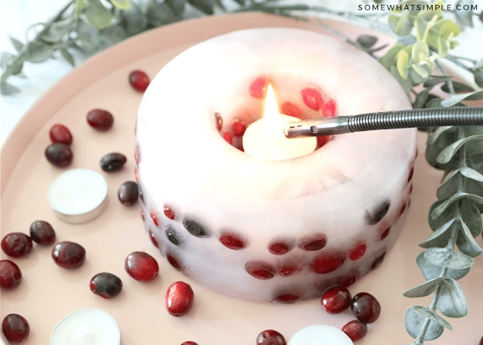 lighting an ice candle with berries and greenery