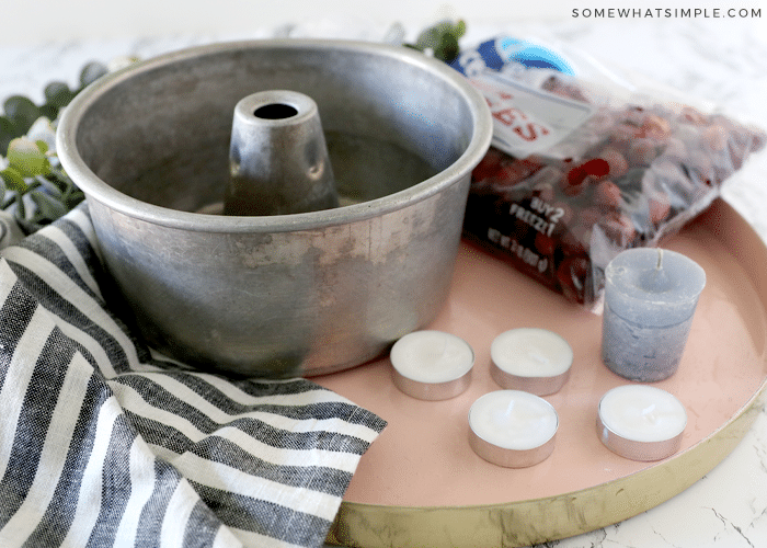 angel food cake pan next to cranberries and candles on a counter with a round tray