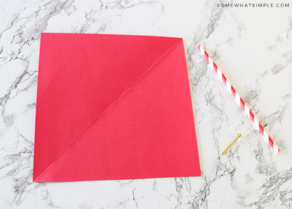 piece of red paper on the counter with a straw next to it