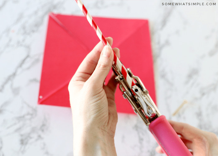 using a hole punch to put a hole in a paper straw