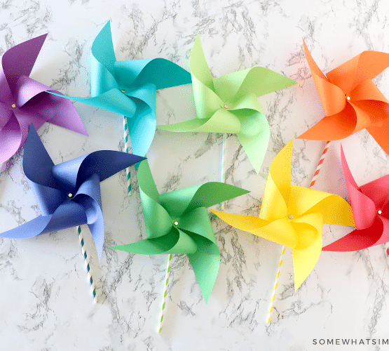 8 paper pinwheels in different colors of the rainbow laying on the counter