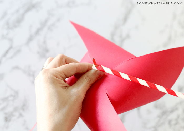 making a paper pinwheel with red paper and a paper straw