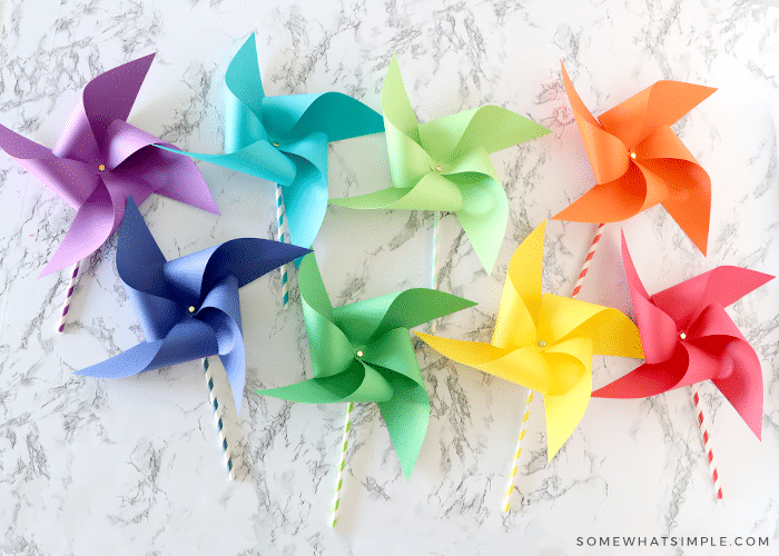 8 paper pinwheels in different colors of the rainbow laying on the counter