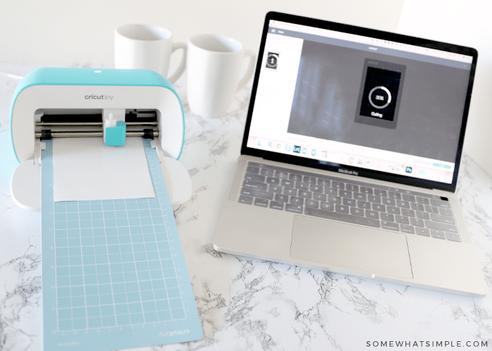 cutting machine next to a laptop cutting some white vinyl