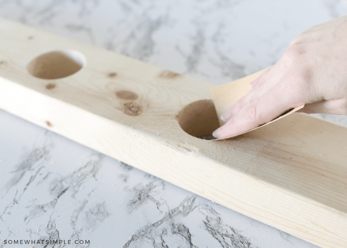 sanding a piece of wood with holes drilled into it