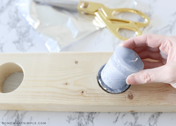 placing a candle inside a wood board that has been drilled