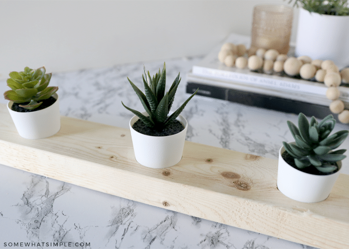 three faux succulents in a wood board