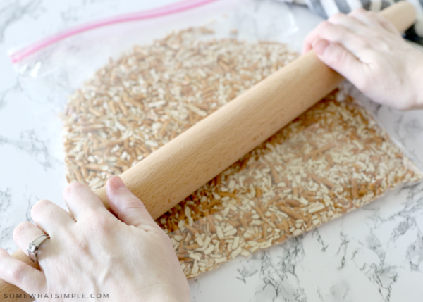 crushed pretzels in a plastic bag with a rolling pin