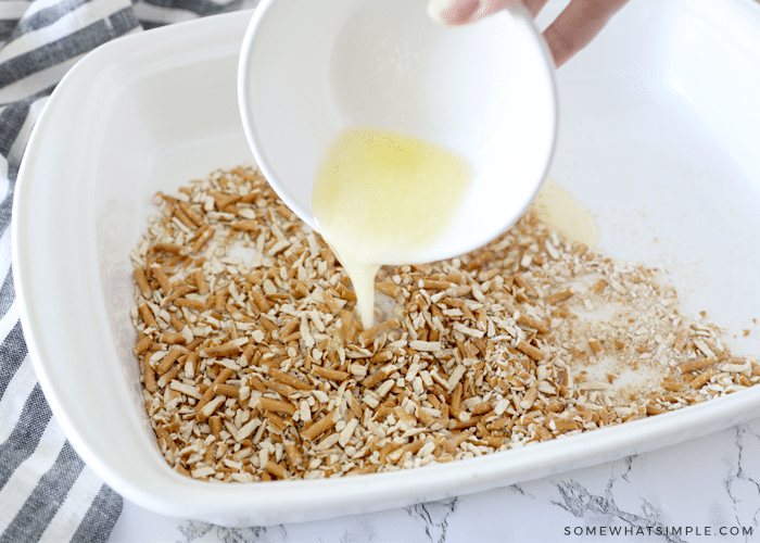 pouring melted butter on top of pretzel crumbs in a white baking pan