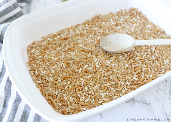 pressing pretzel crumbs into a baking pan with a wooden spoon