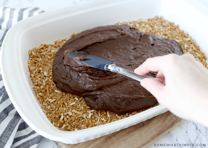 spreading brownie mixture on top of a pretzel crust