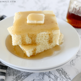 sheet pan pancakes topped with butter on a white plate covered in syrup