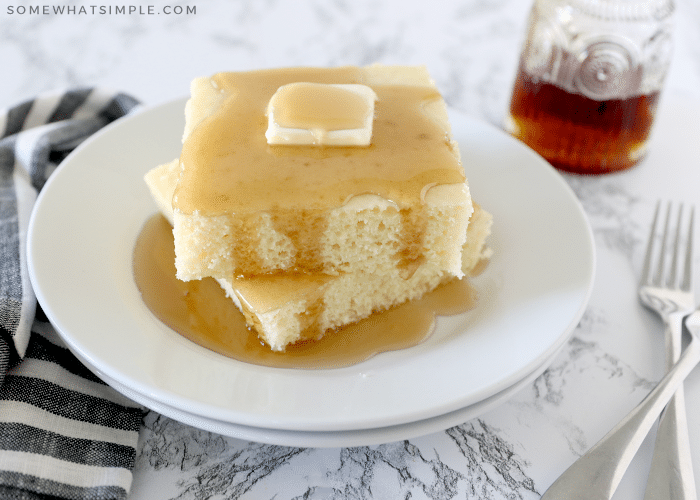 sheet pan pancakes topped with butter on a white plate covered in syrup