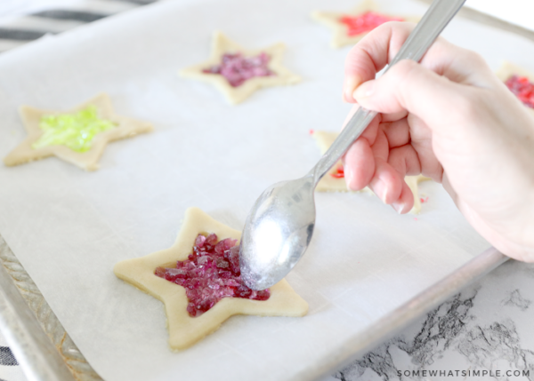 adding crushed candies to the centers of raw cookie dough in the shape of a star