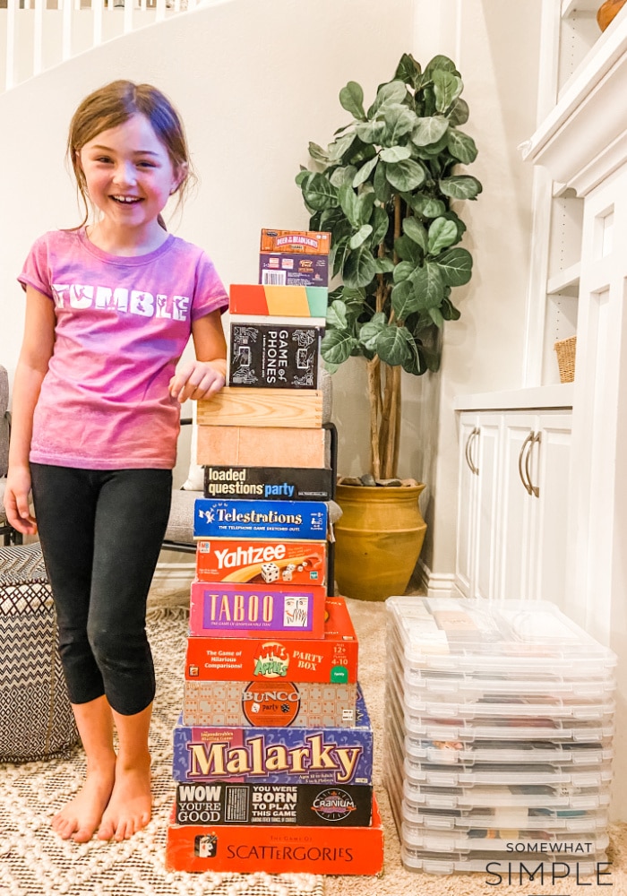 little girl standing next to a pile of board games