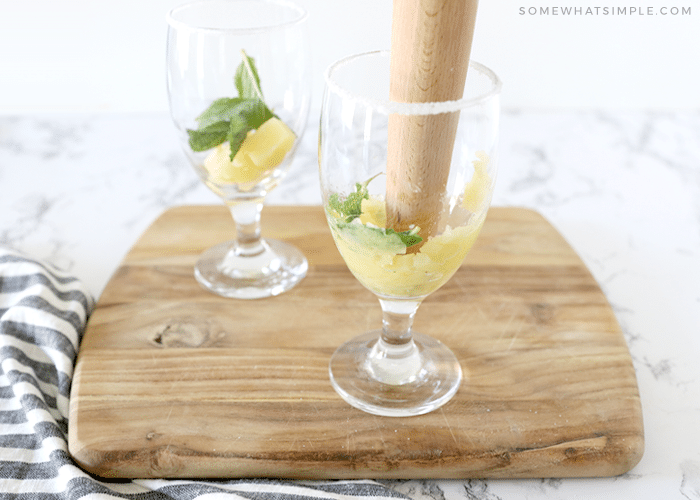 muddling pineapple chunks with mint leaves