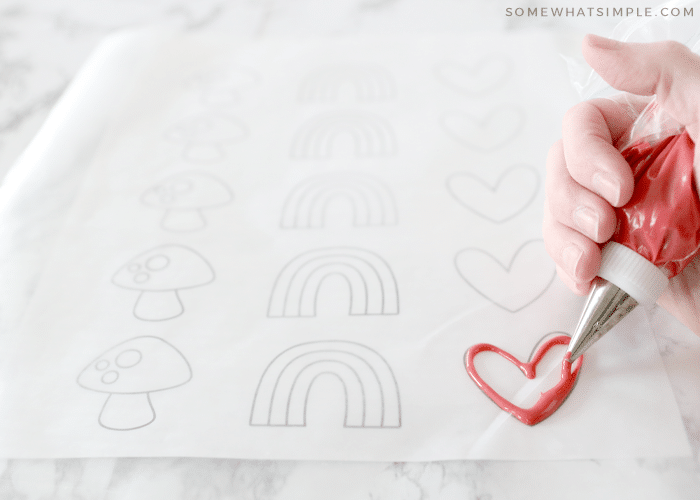 wax paper over a template with frosting being piped onto the design