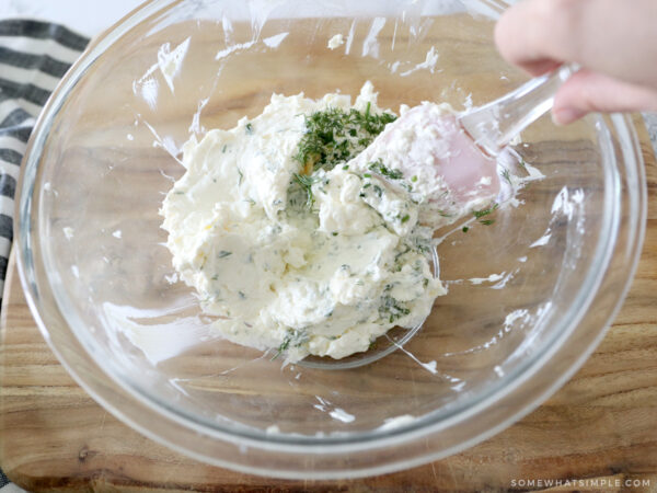 adding fresh herbs to a cream cheese mixture