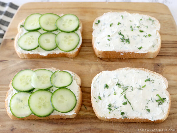 laying out cucumber and herbed cream cheese on slices of white bread