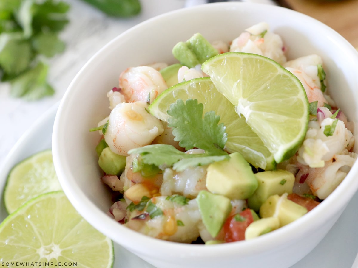 shrimp avocado salad in a white bowl with lime slices