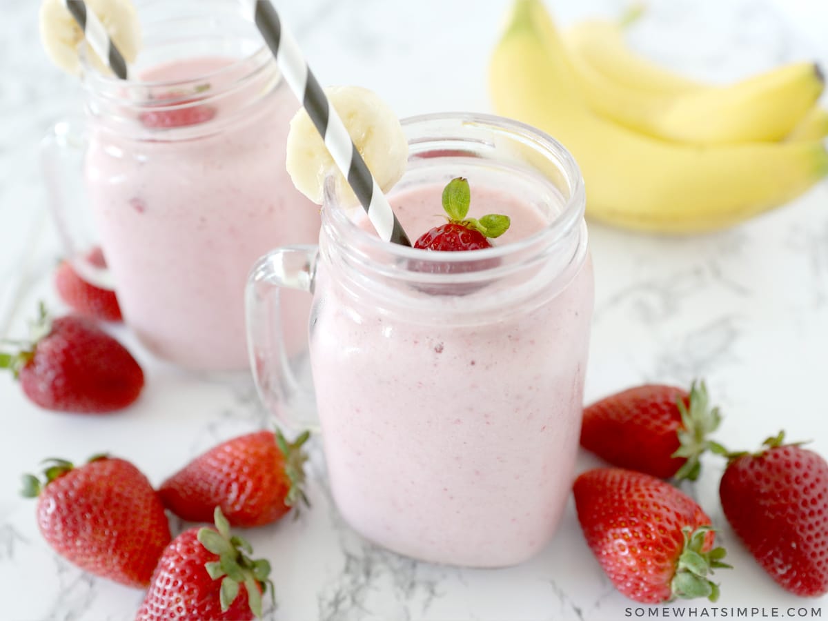 two smoothies on a counter with fresh fruit