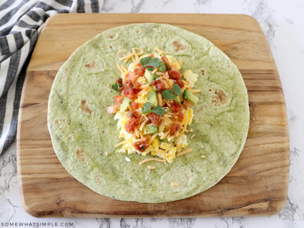 breakfast wrap ingredients in the center of a spinach tortilla