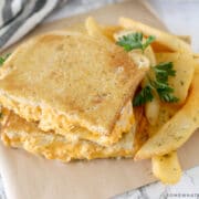 close up of a buffalo chicken grilled cheese sandwich with steak fries