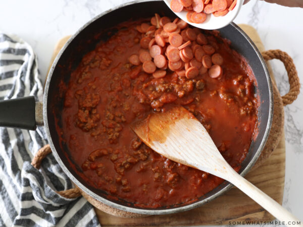 adding pepperoni to meat and sauce