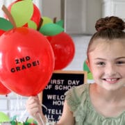 little girl holding red balloon with 2nd grade sign on it