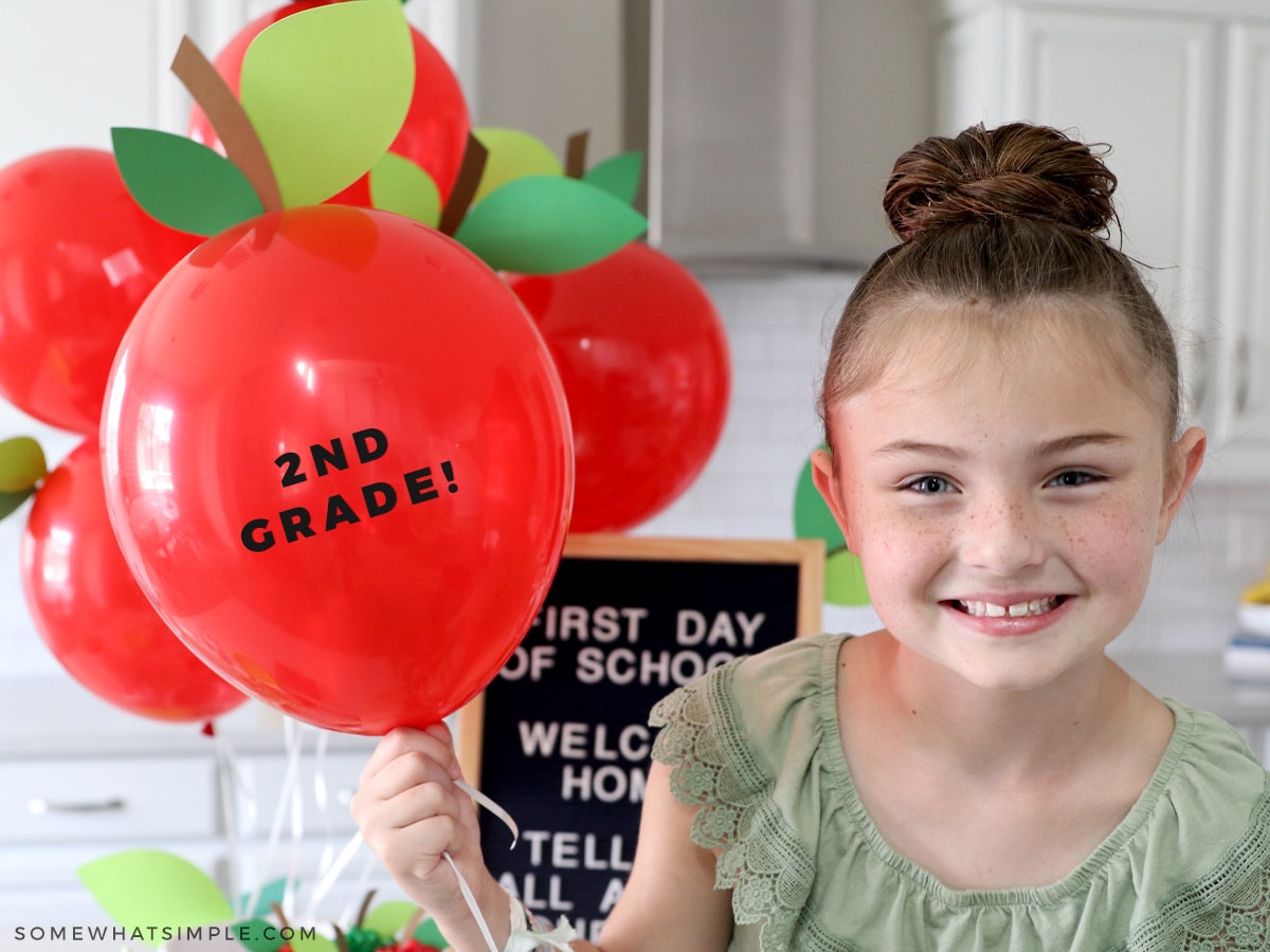 little girl holding red balloon with 2nd grade sign on it