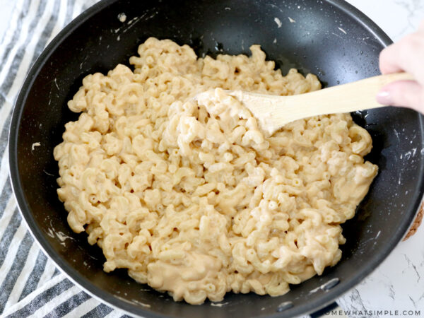 adding macaroni noodles to cheese sauce