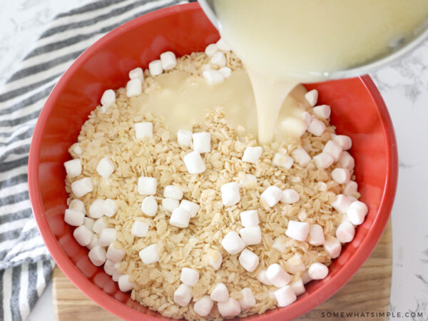 adding brown butter mixture to a bowl of rice krispies