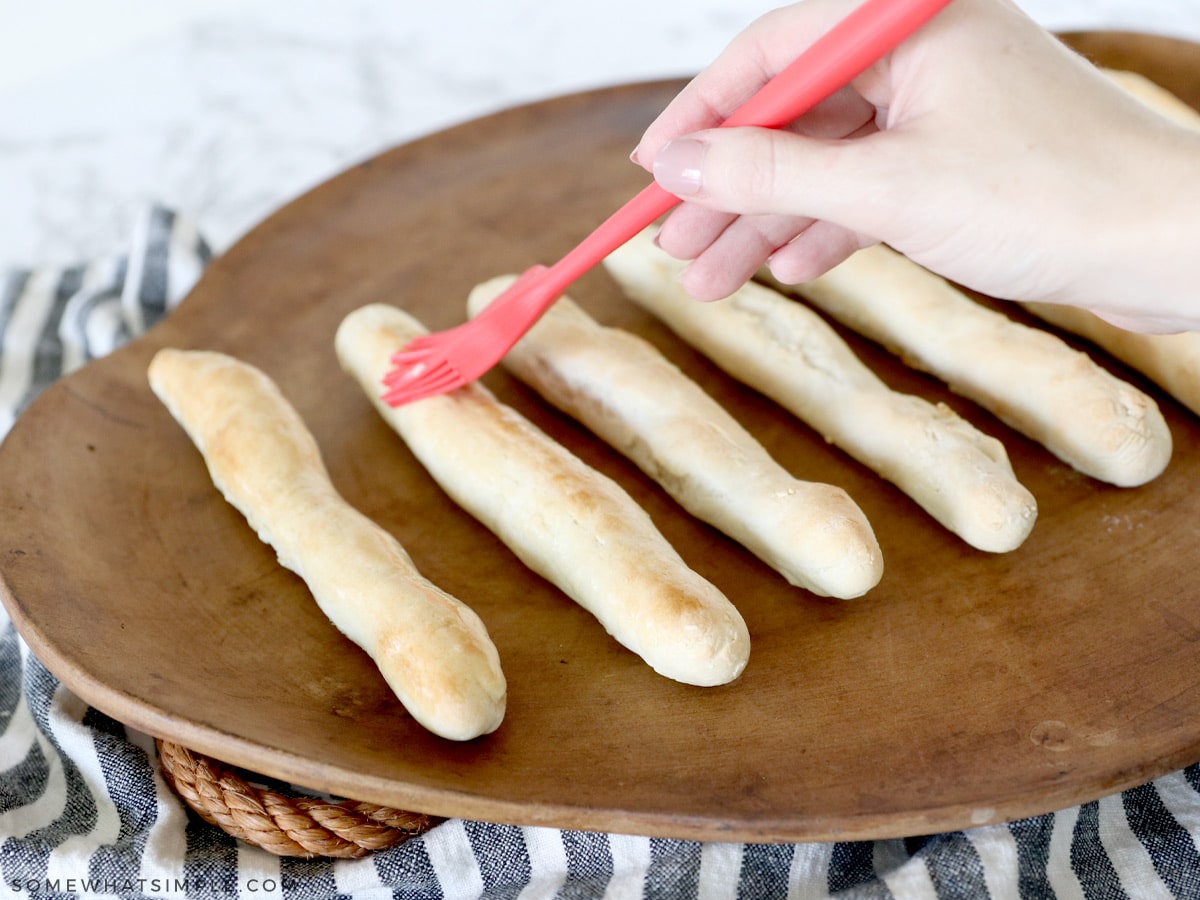 seasoning and brushing breadsticks with butter