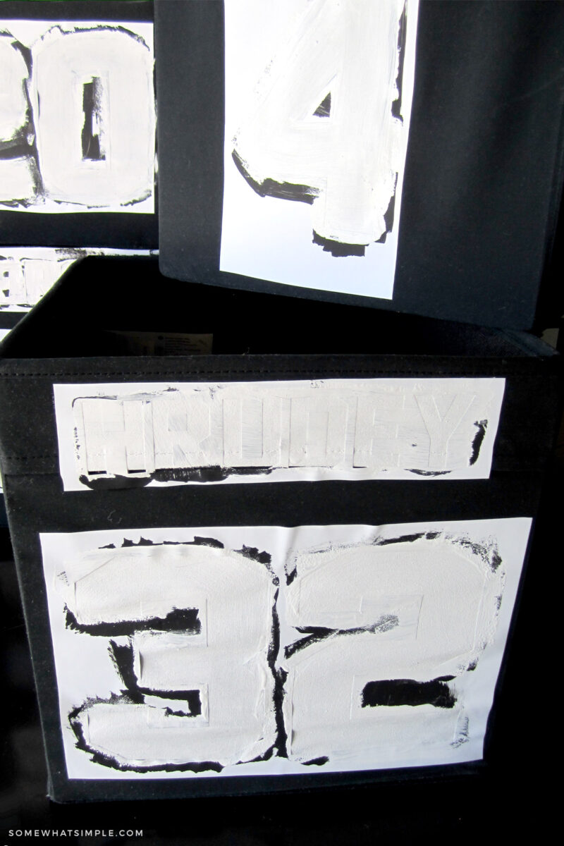 painting white numbers on black bins