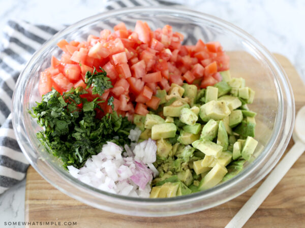 adding all the ingredients of guacamole salsa to a bowl