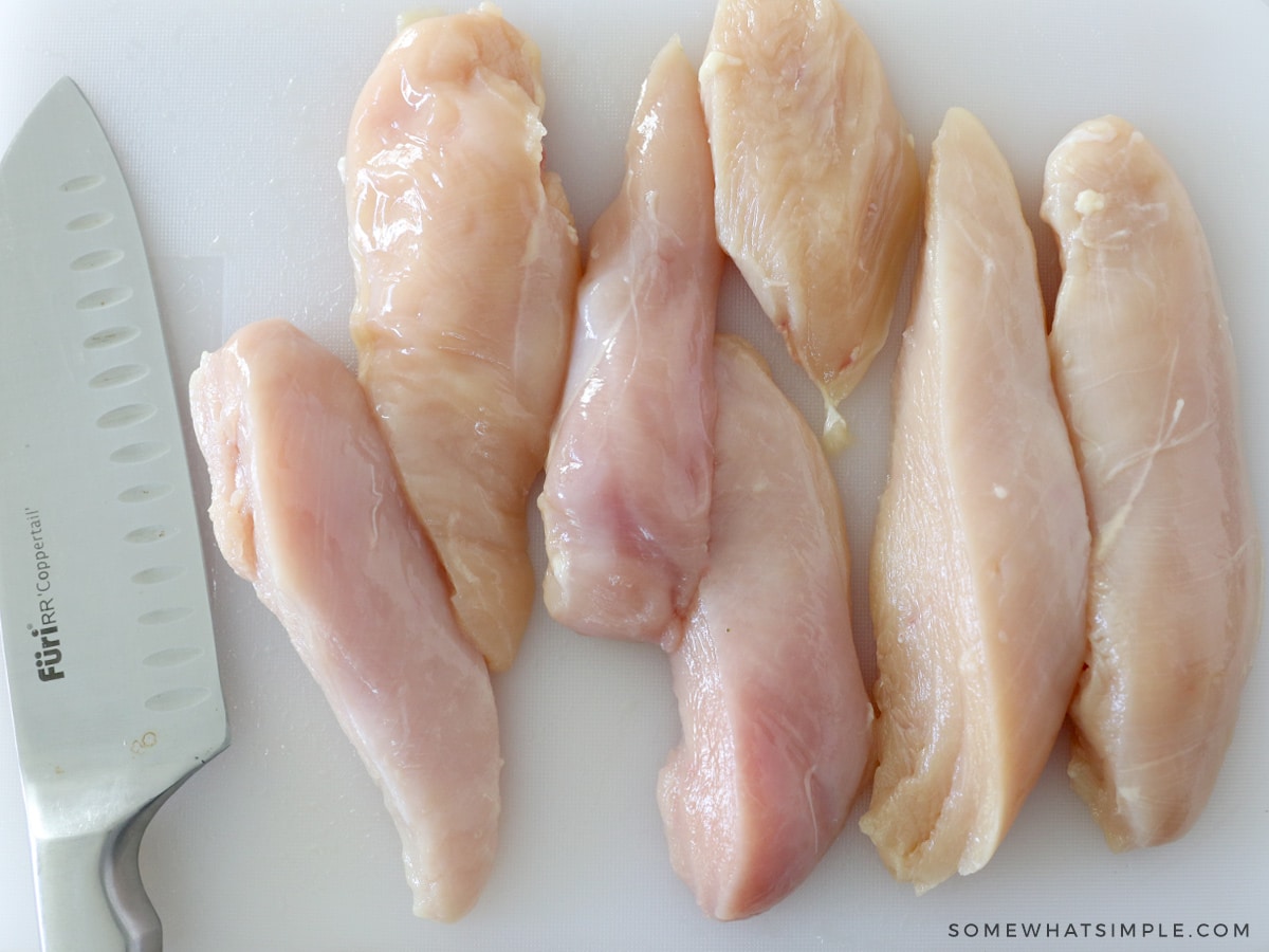 raw chicken cutlets on a white cutting board