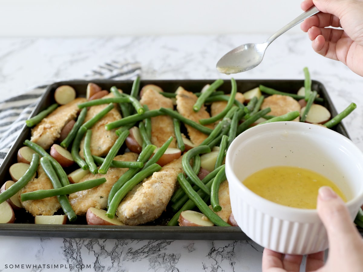 adding green beans to a baking sheet and drizzling with butter