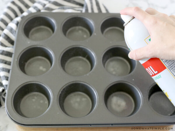 spraying a muffin tin with nonstick spray