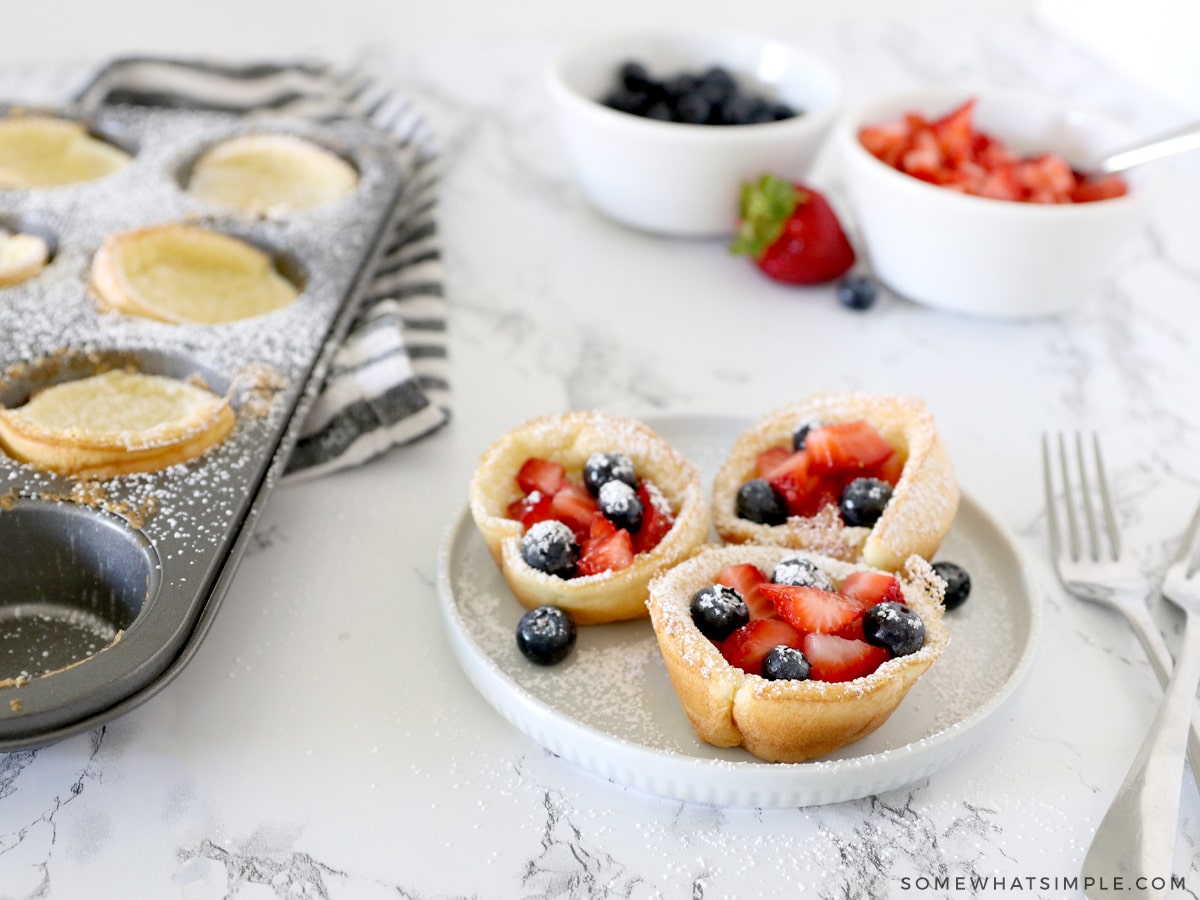 mini dutch baby pancakes topped with berries and sugar