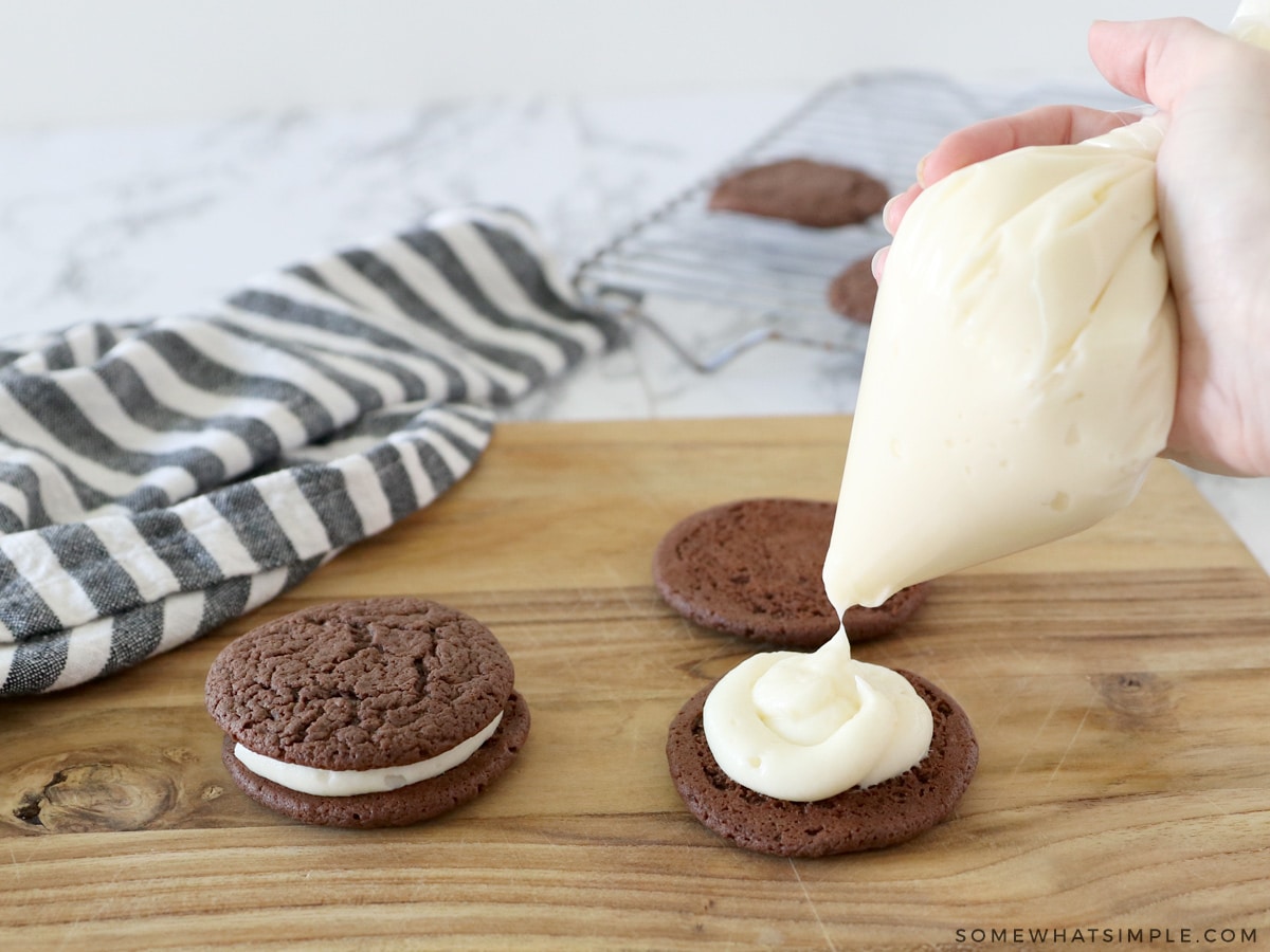 piping cream cheese frosting onto homemade oreos