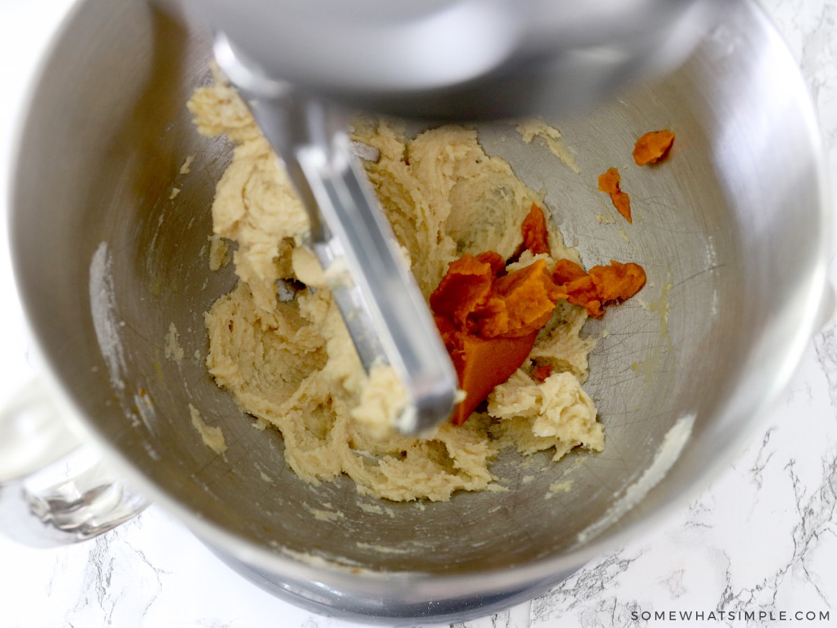 adding pumpkin puree to sugar cookie ingredients